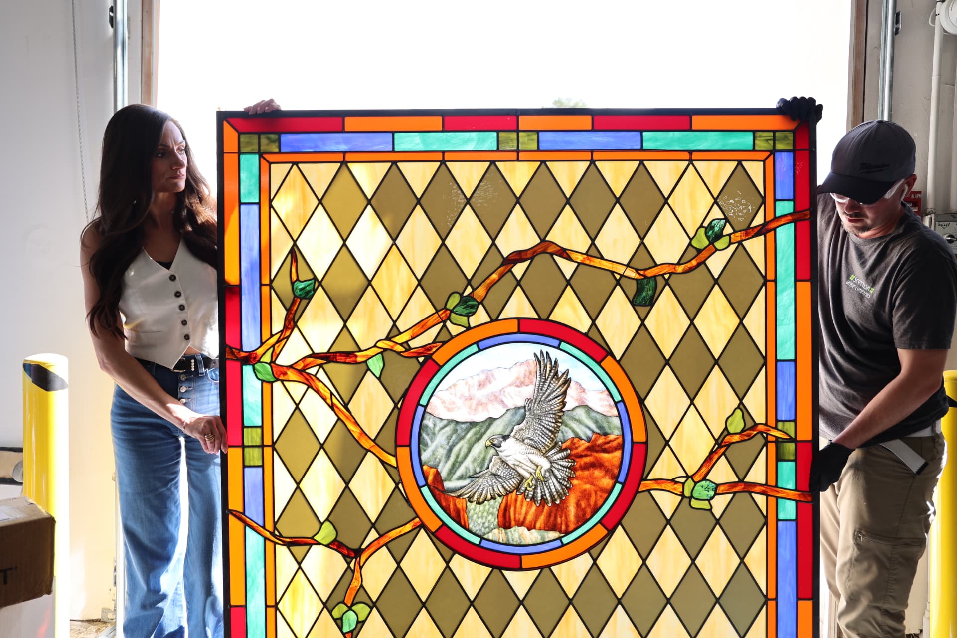 Brooke Fergus and a Scottish Stained Glass craftsperson holding the Angelo's Taverna stained glass panel