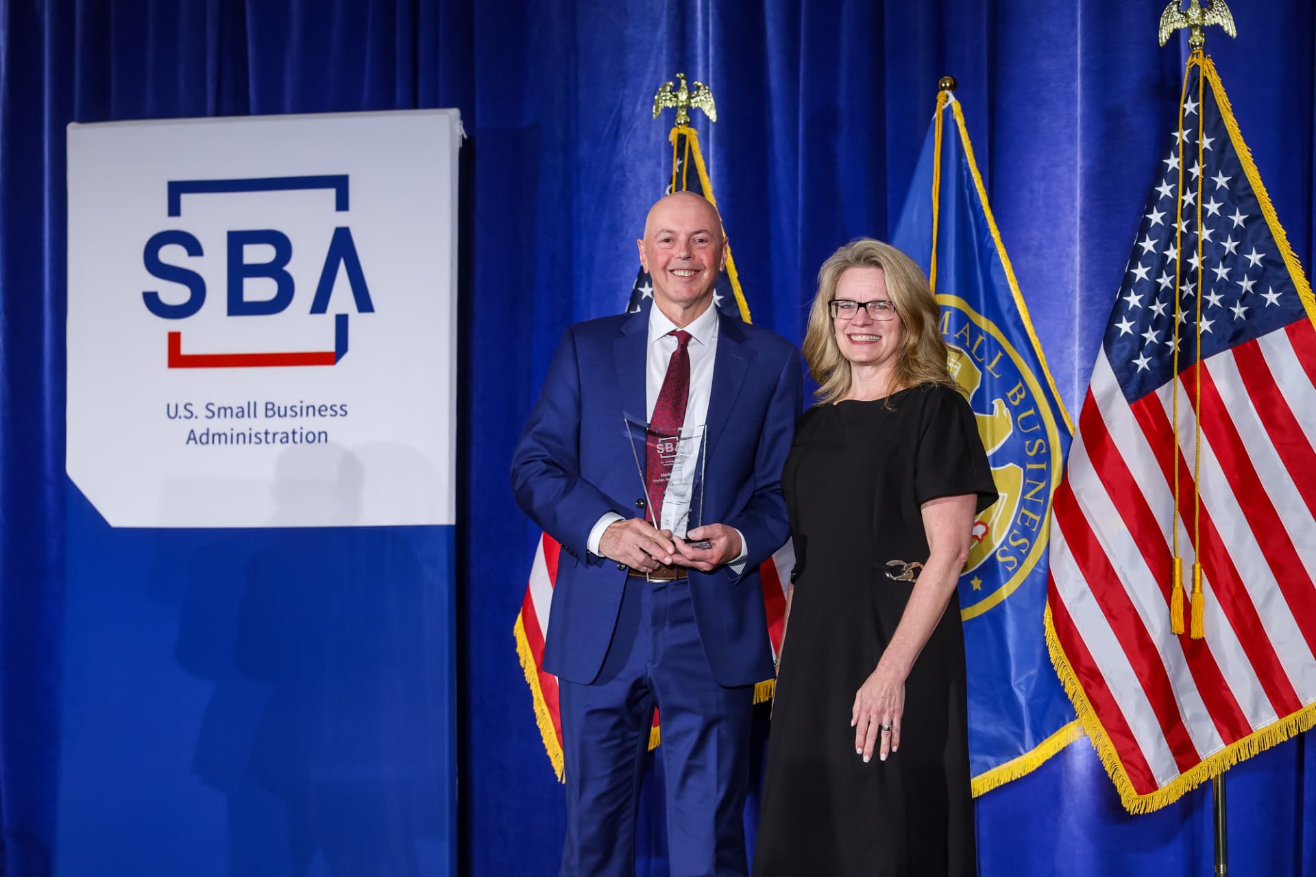 Martin Faith holding the SBA award beside an SBA representative at the ceremony