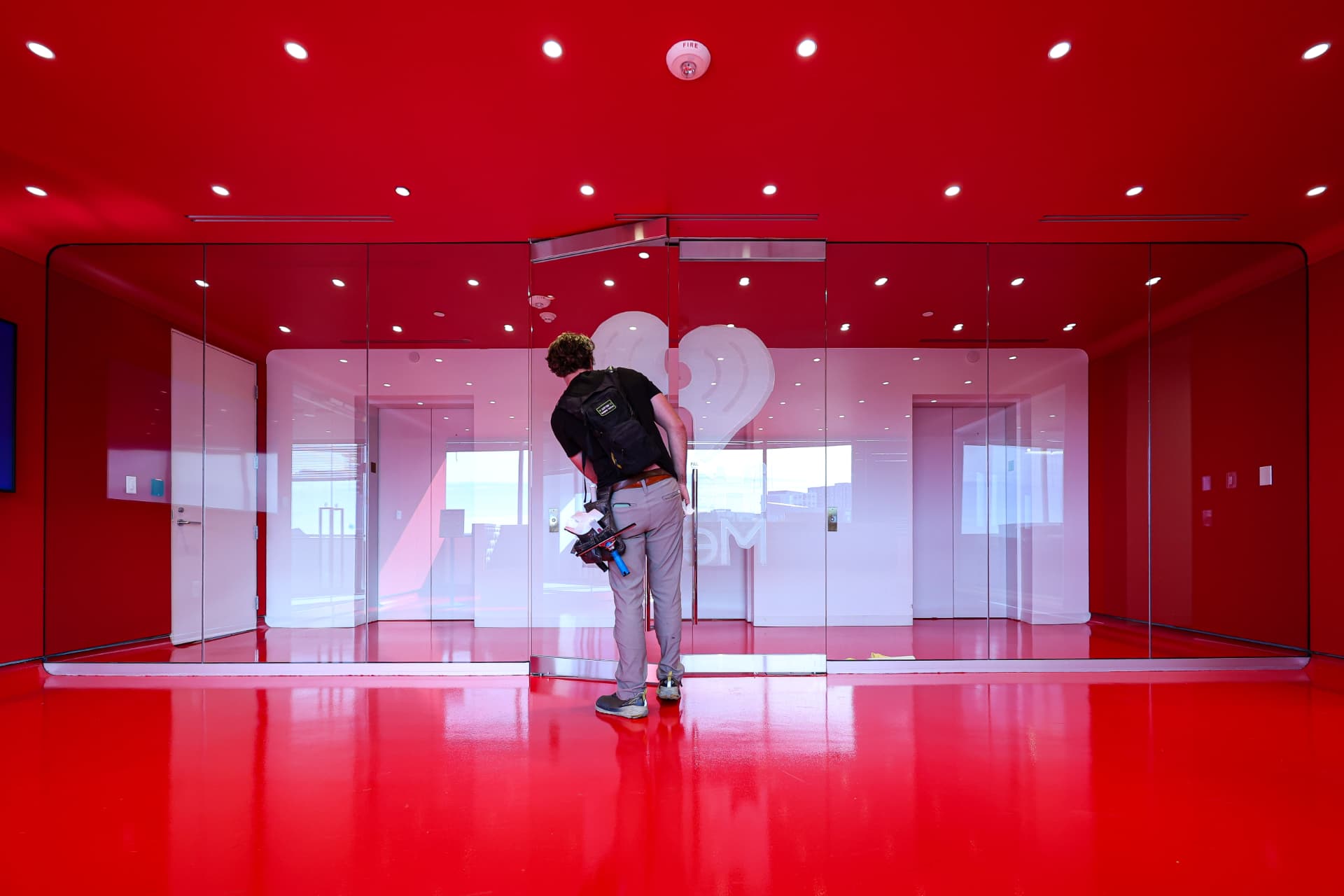 Installer applying privacy film to interior glass walls in a bold red commercial space